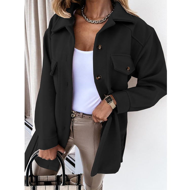 Femme portant une veste noire élégante, chemise blanche, pantalon beige, avec un sac à main à carreaux. Mode automne chic et tendance.