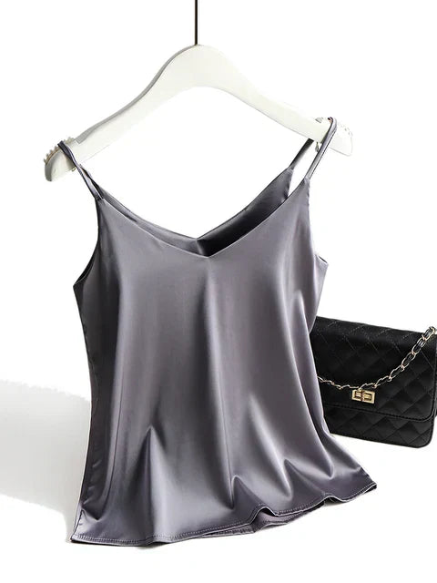 Débardeur en satin gris sur cintre, avec sac à main noir matelassé à chaîne dorée. Mode féminine élégante, vêtements tendance.