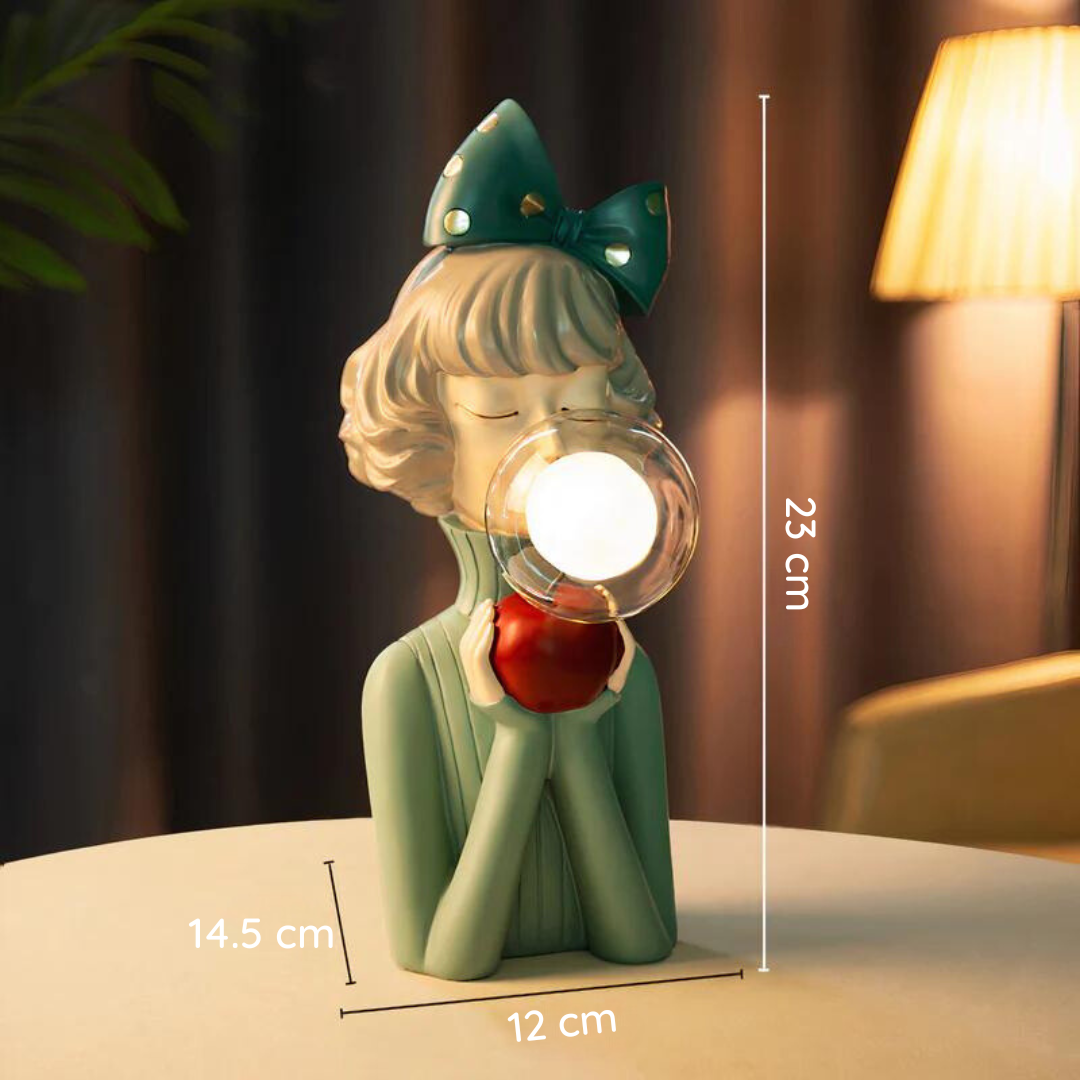 Statue décorative de fille en résine verte avec pomme rouge et bulle, éclairée par une lampe, dimensions 23x14,5x12 cm, design moderne et élégant.
