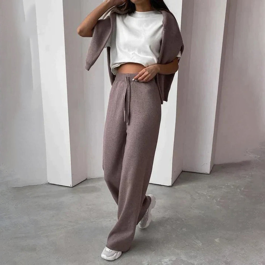 Femme portant un ensemble décontracté marron, composé d'un pantalon ample et d'un haut court, posant dans un intérieur moderne. Mode confortable.