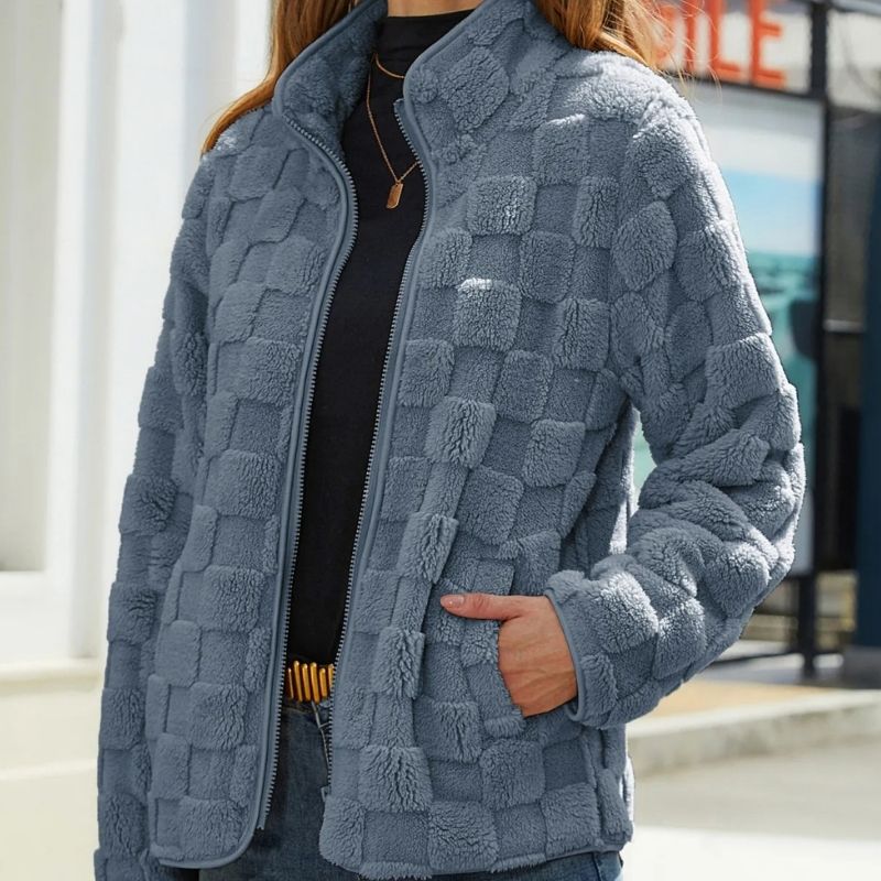 Veste en polaire grise à carreaux, femme, mode automne, tenue décontractée, texture douce, fermeture éclair, poches latérales, style moderne.