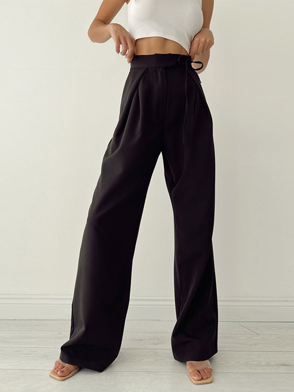 Pantalon large noir taille haute, femme en haut blanc, style décontracté chic, mode féminine moderne, tendance élégante, fond blanc minimaliste.