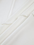 Tissu blanc en coton texturé, gros plan sur les plis et les détails de la matière. Idéal pour mode, couture, textile de haute qualité.