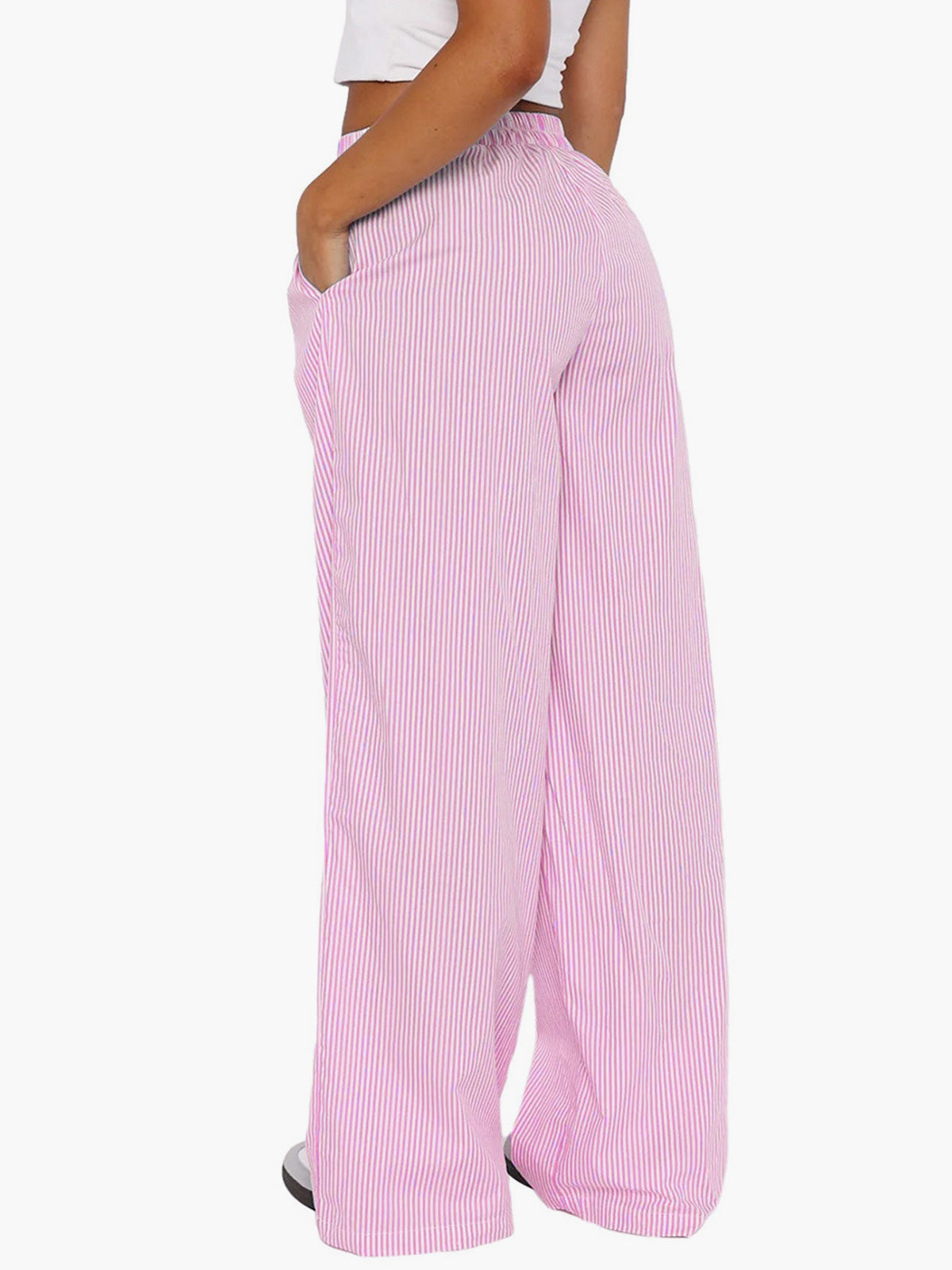 Pantalon large rose à rayures blanches, taille haute, porté par une femme. Mode décontractée, tendance, confortable, idéal pour l'été.