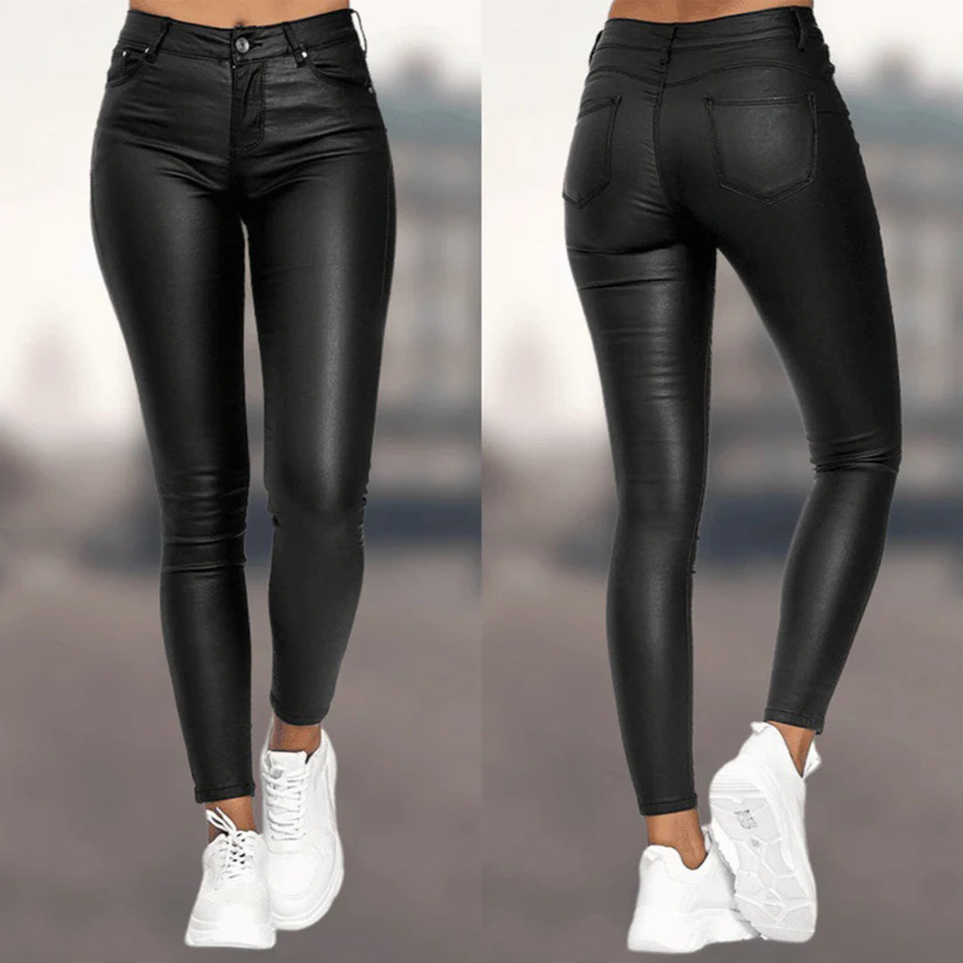 Pantalon en similicuir noir pour femme, coupe slim, taille haute, avec poches arrière, porté avec des baskets blanches. Mode tendance et élégante.