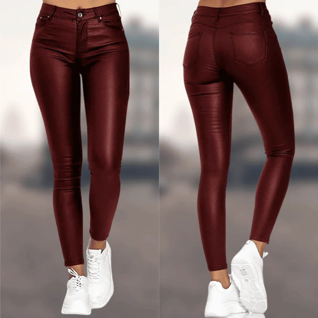 Pantalon skinny en cuir bordeaux pour femme, taille haute, avec poches arrière, porté avec des baskets blanches. Mode tendance automne-hiver.