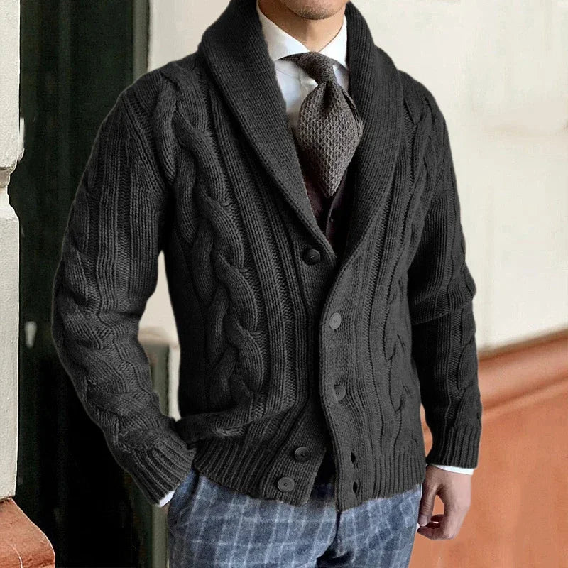 Homme portant un cardigan en maille torsadée noir, élégant et chic, avec cravate et chemise blanche. Mode masculine automne-hiver tendance.