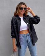Jeune femme souriante portant une chemise en jean noir délavé, un crop top blanc et un jean bleu, accessoirisée de lunettes de soleil noires.