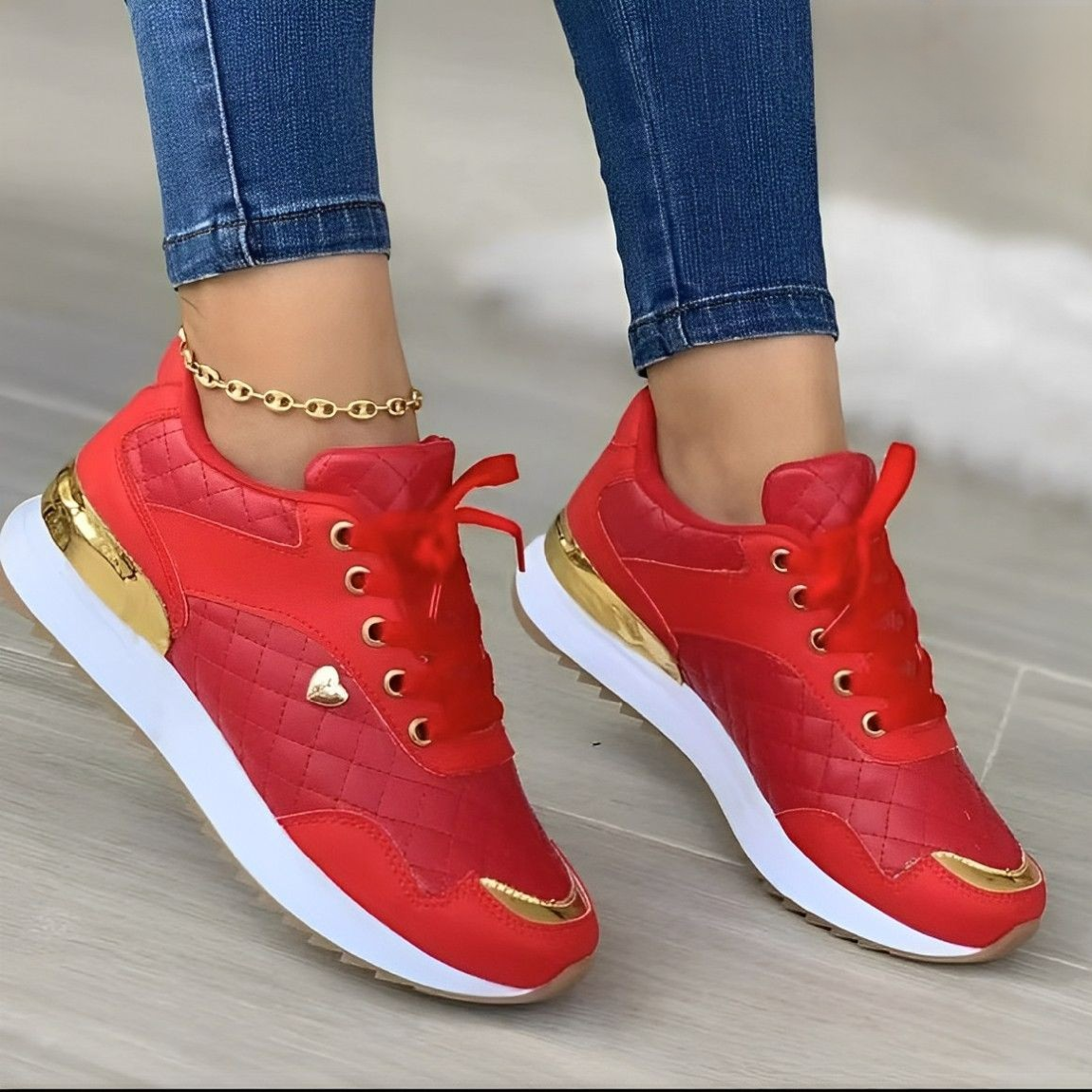 Baskets rouges élégantes avec détails dorés, portées avec un jean ajusté. Chaussures de sport tendance pour femme, style moderne et chic.