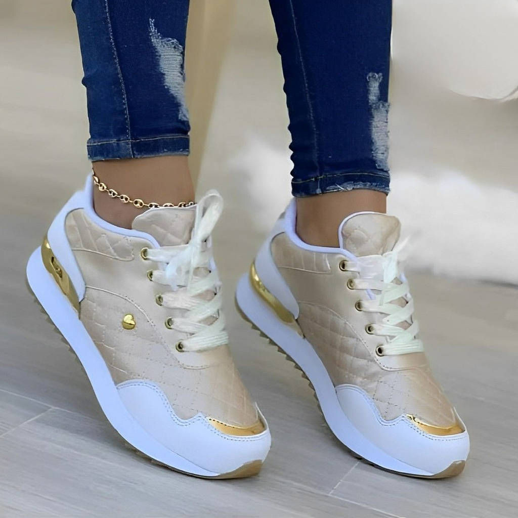 Chaussures de sport dorées pour femme avec détails blancs et dorés, portées avec un jean déchiré. Style moderne et tendance.