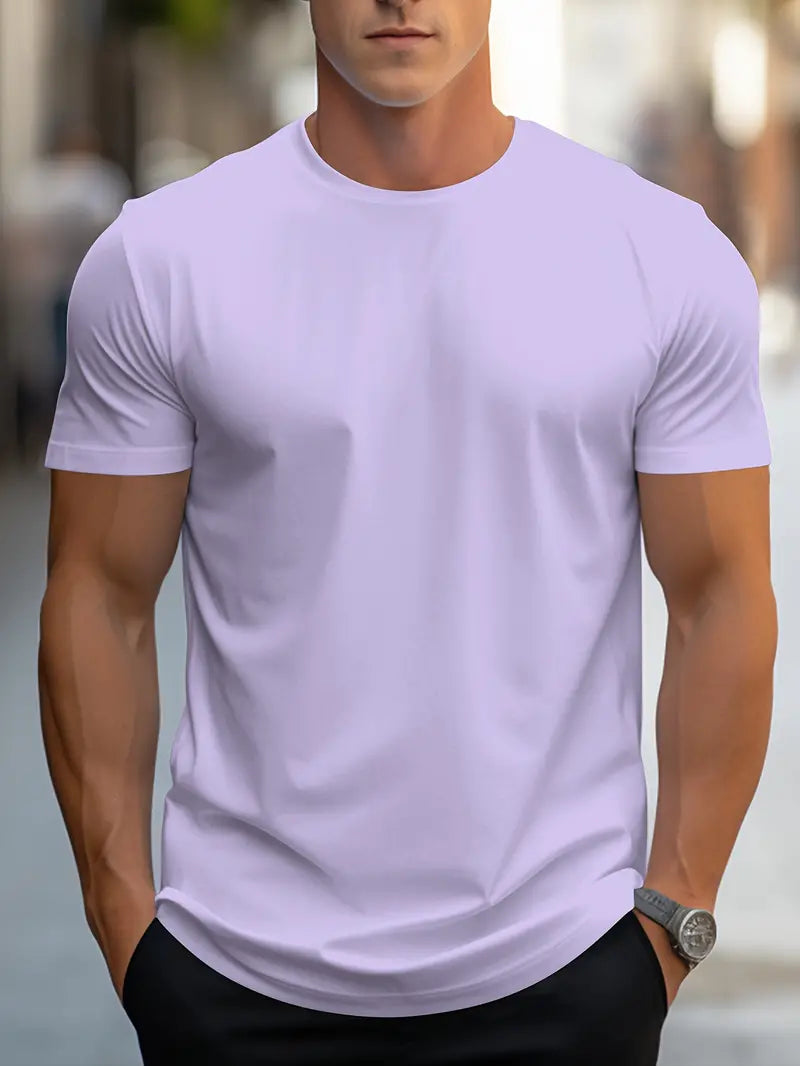 Homme portant un t-shirt blanc ajusté, manches courtes, en extérieur urbain. Mode masculine, style décontracté, tenue d'été.