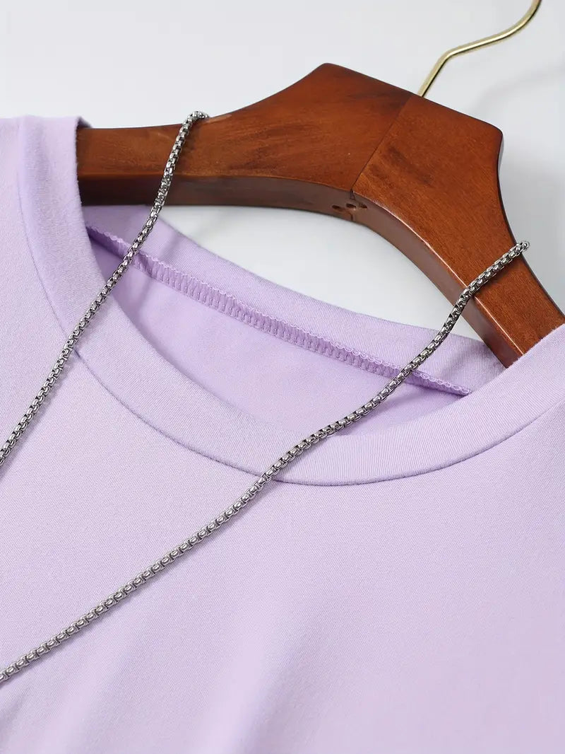 T-shirt violet en coton sur cintre en bois, avec collier chaîne argentée. Mode féminine, vêtement décontracté, tendance printemps-été.