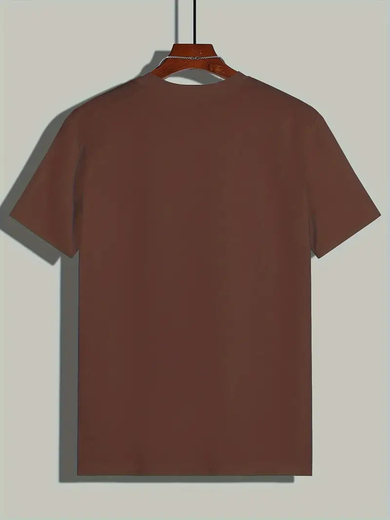 T-shirt marron uni suspendu sur un cintre en bois, fond gris. Mode décontractée, vêtement basique, style minimaliste, prêt-à-porter.