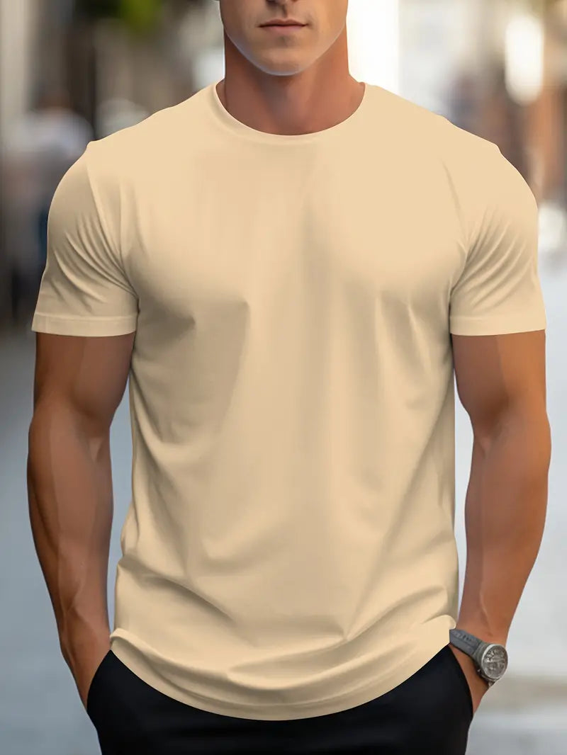 Homme portant un t-shirt beige ajusté, manches courtes, en extérieur urbain. Mode masculine, style décontracté, tendance vêtements homme.