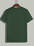 T-shirt vert uni pour homme suspendu sur un cintre en bois, arrière-plan gris clair. Mode décontractée, vêtement basique, style minimaliste.