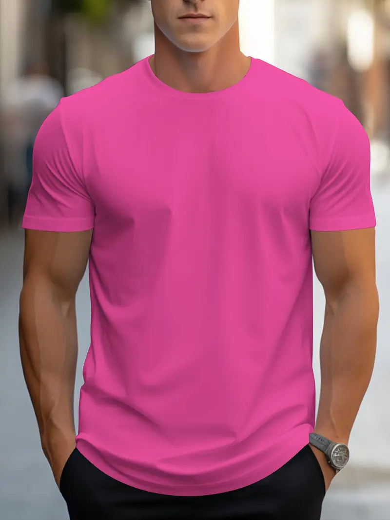 Homme portant un t-shirt rose vif, manches courtes, sur fond urbain flou. Mode masculine, tenue décontractée, style moderne.