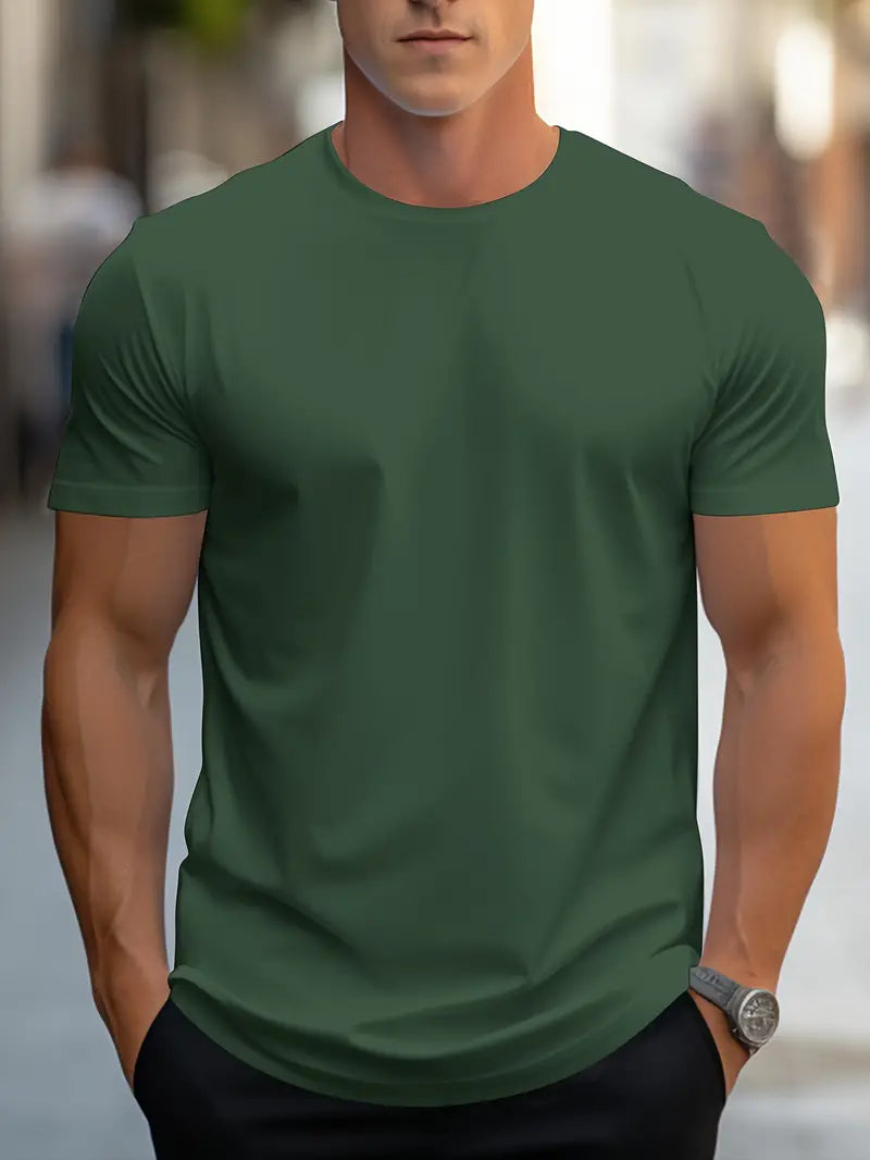 Homme portant un t-shirt vert uni, manches courtes, sur fond urbain flou. Mode masculine décontractée, style moderne, tenue quotidienne.