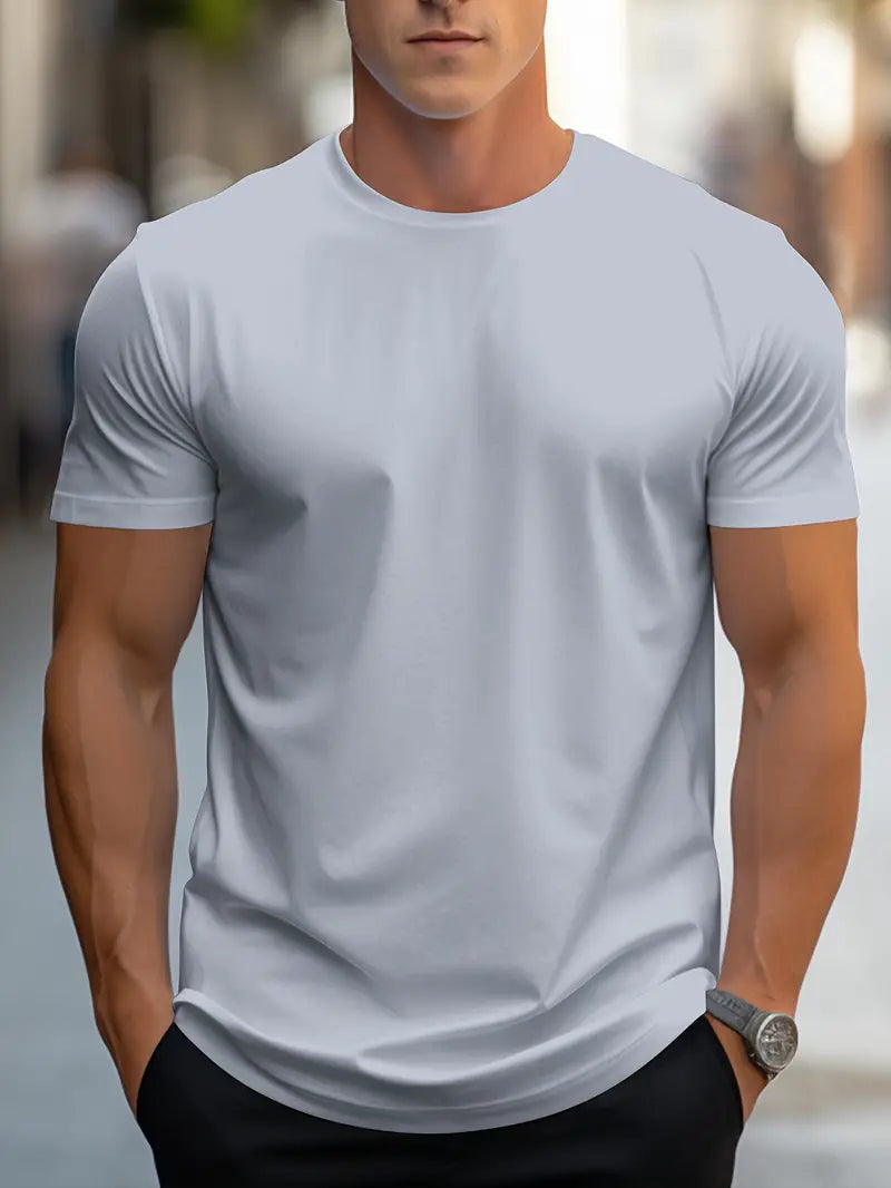 Homme portant un t-shirt blanc ajusté, manches courtes, dans une rue urbaine. Mode masculine, style décontracté, tenue d'été élégante.
