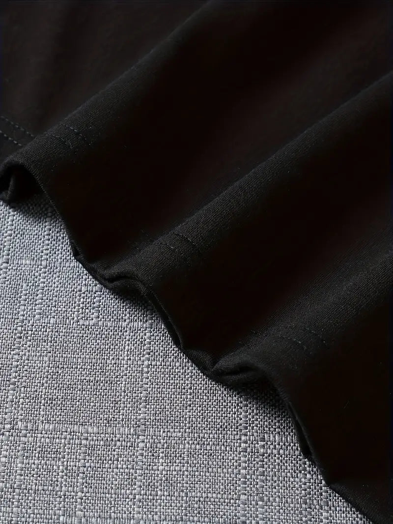 T-shirt noir en coton doux, posé sur un tissu gris texturé. Mode décontractée, vêtement basique, style minimaliste, confort quotidien.