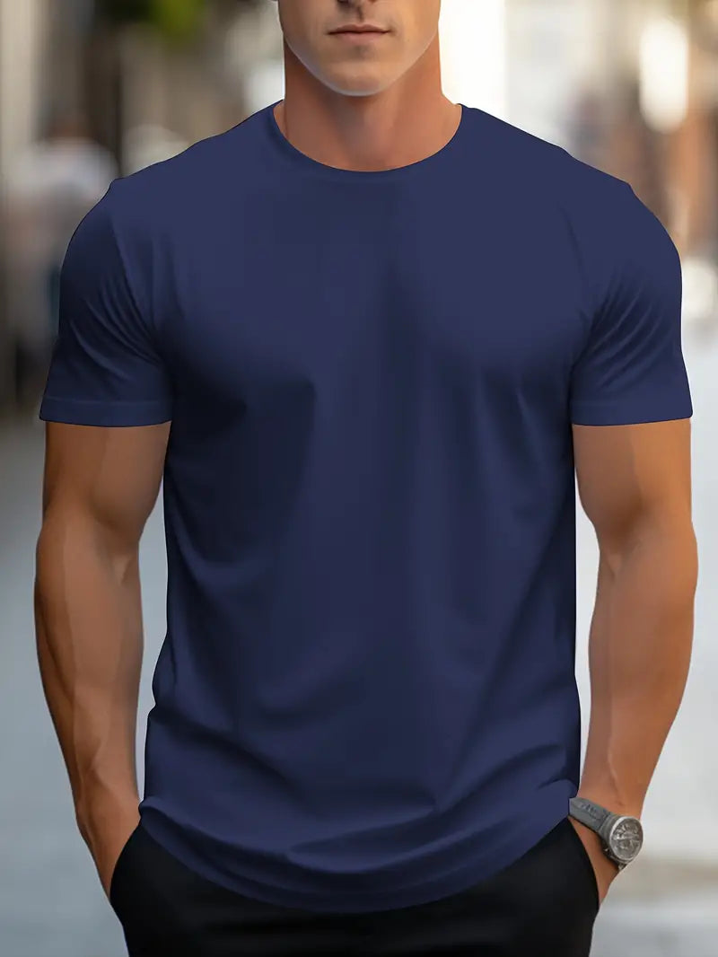Homme portant un t-shirt bleu marine uni, manches courtes, en extérieur urbain. Mode masculine, style décontracté, montre argentée visible.