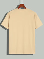 T-shirt beige uni pour homme, manches courtes, col rond, suspendu sur un cintre en bois. Mode décontractée, vêtement basique, style minimaliste.