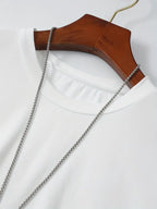 T-shirt blanc en coton sur cintre en bois avec chaîne argentée, mode minimaliste, vêtement basique, style décontracté, accessoire tendance.