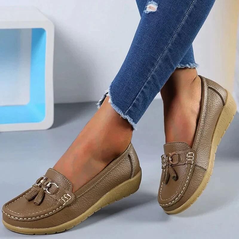 Chaussures mocassins marron pour femme, en cuir texturé, avec pampilles, portées avec un jean déchiré. Mode féminine, confort, style décontracté.