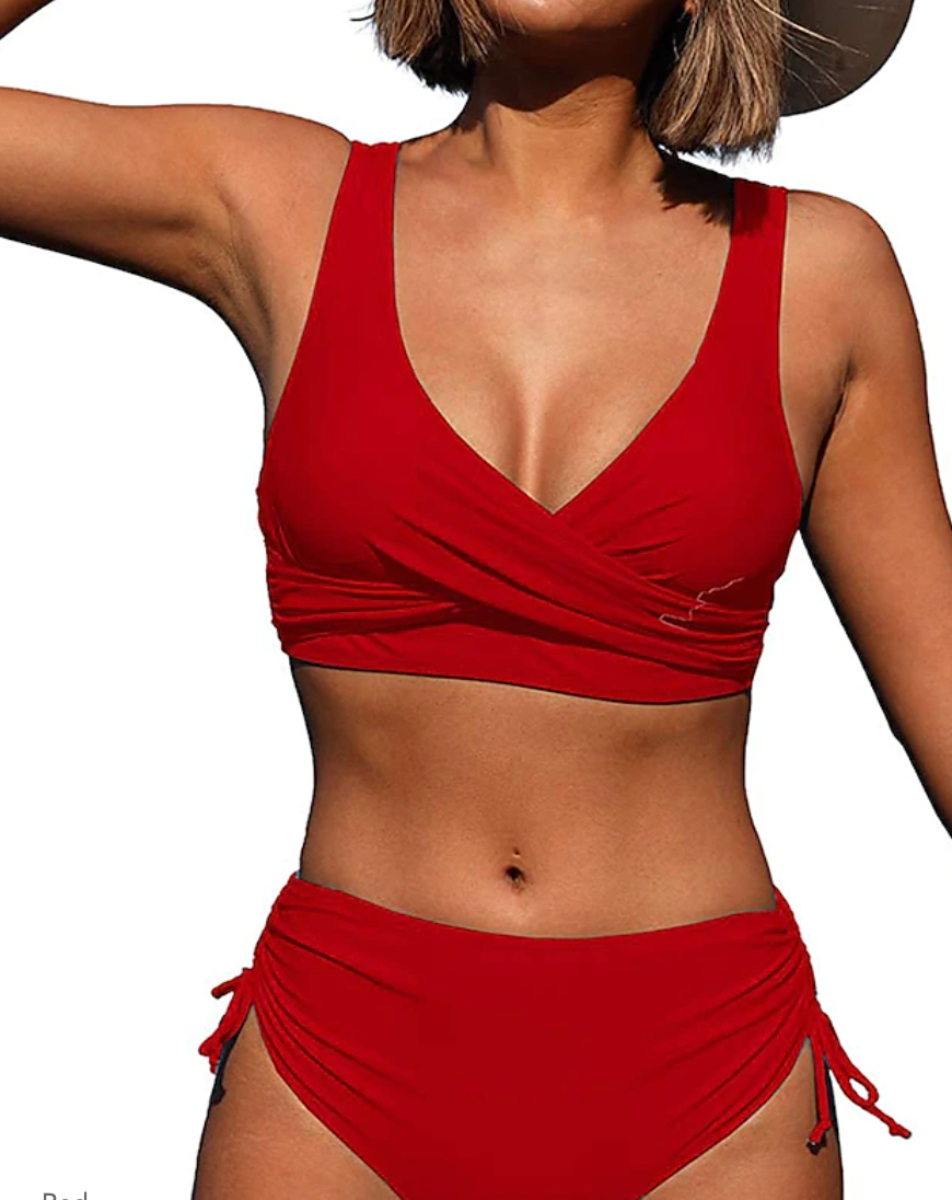 Femme en bikini rouge, haut croisé et bas taille haute, posant en extérieur. Mode plage, maillot de bain tendance, été.