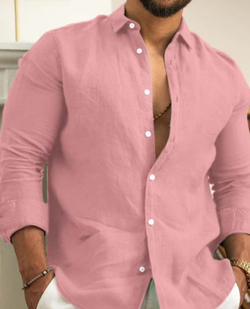 Homme portant une chemise rose en lin, manches retroussées, col ouvert, posant décontracté. Mode masculine élégante et tendance.