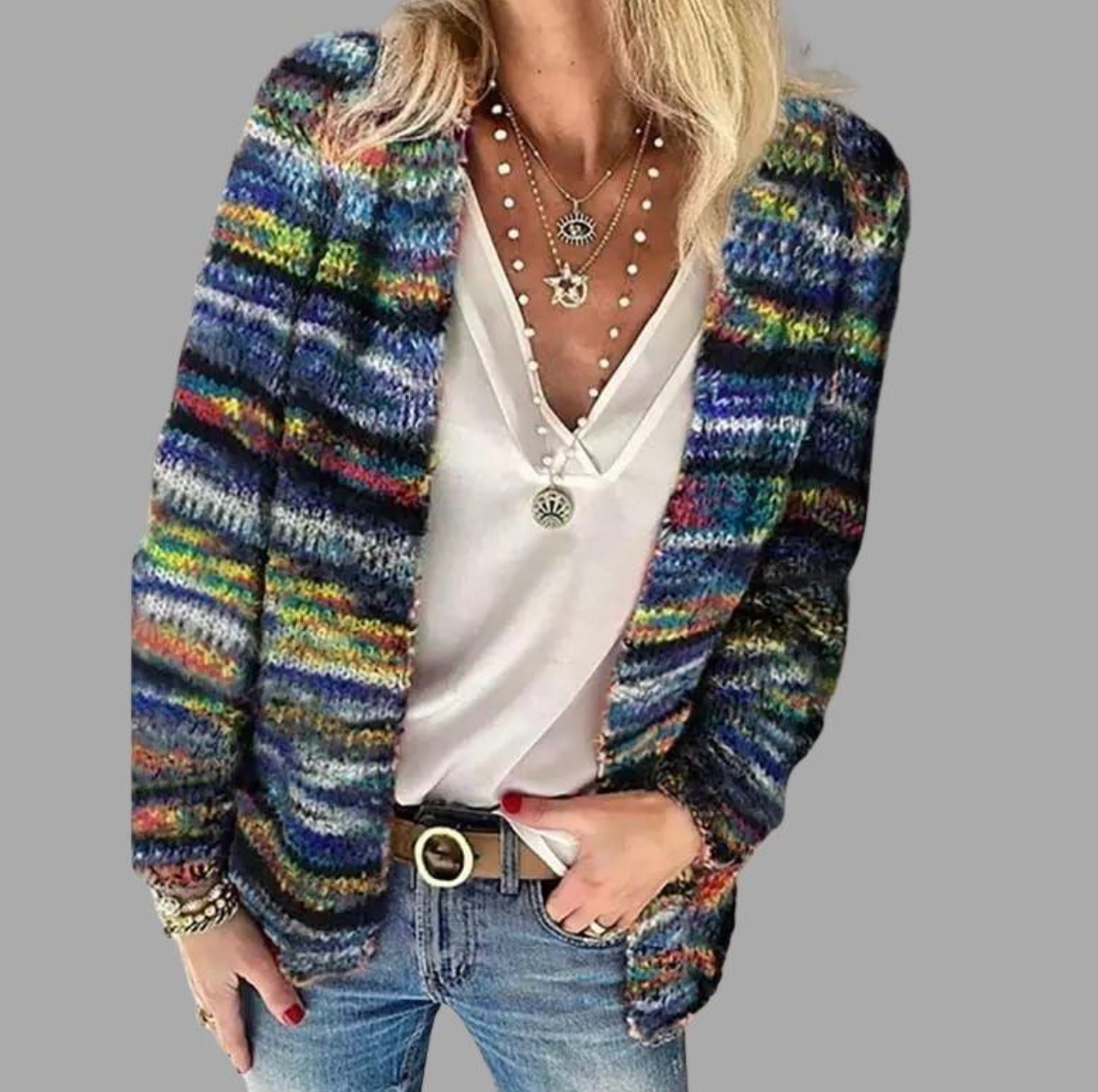 Femme portant un cardigan multicolore en tricot, t-shirt blanc, jeans bleu, colliers superposés. Mode automne, style décontracté chic.