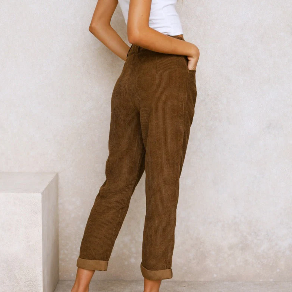 Pantalon en velours côtelé marron pour femme, coupe décontractée, taille haute, avec poches, porté avec un haut blanc. Mode automne-hiver tendance.