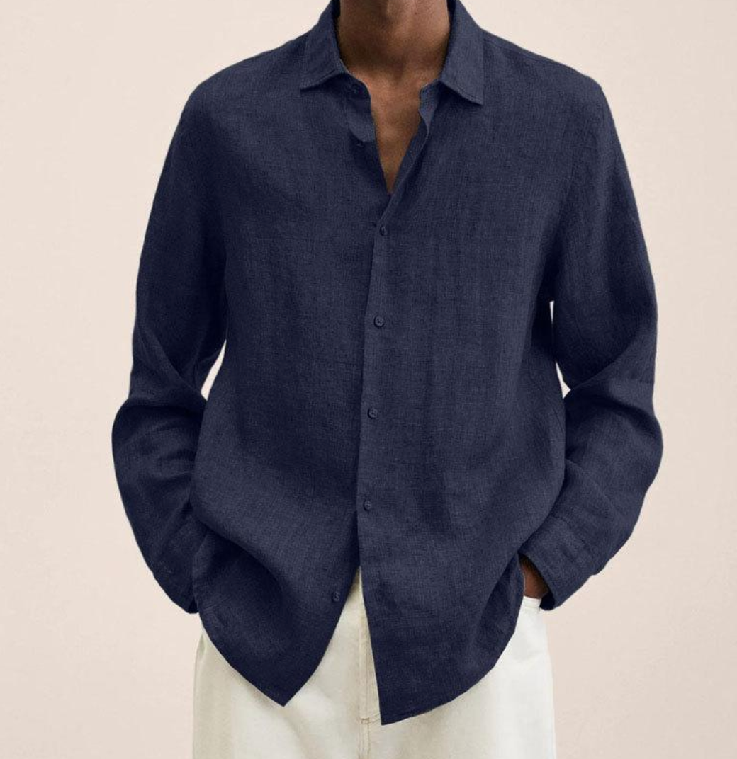 Chemise en lin bleu marine pour homme, manches longues, col ouvert, portée avec un pantalon blanc. Mode élégante et décontractée.