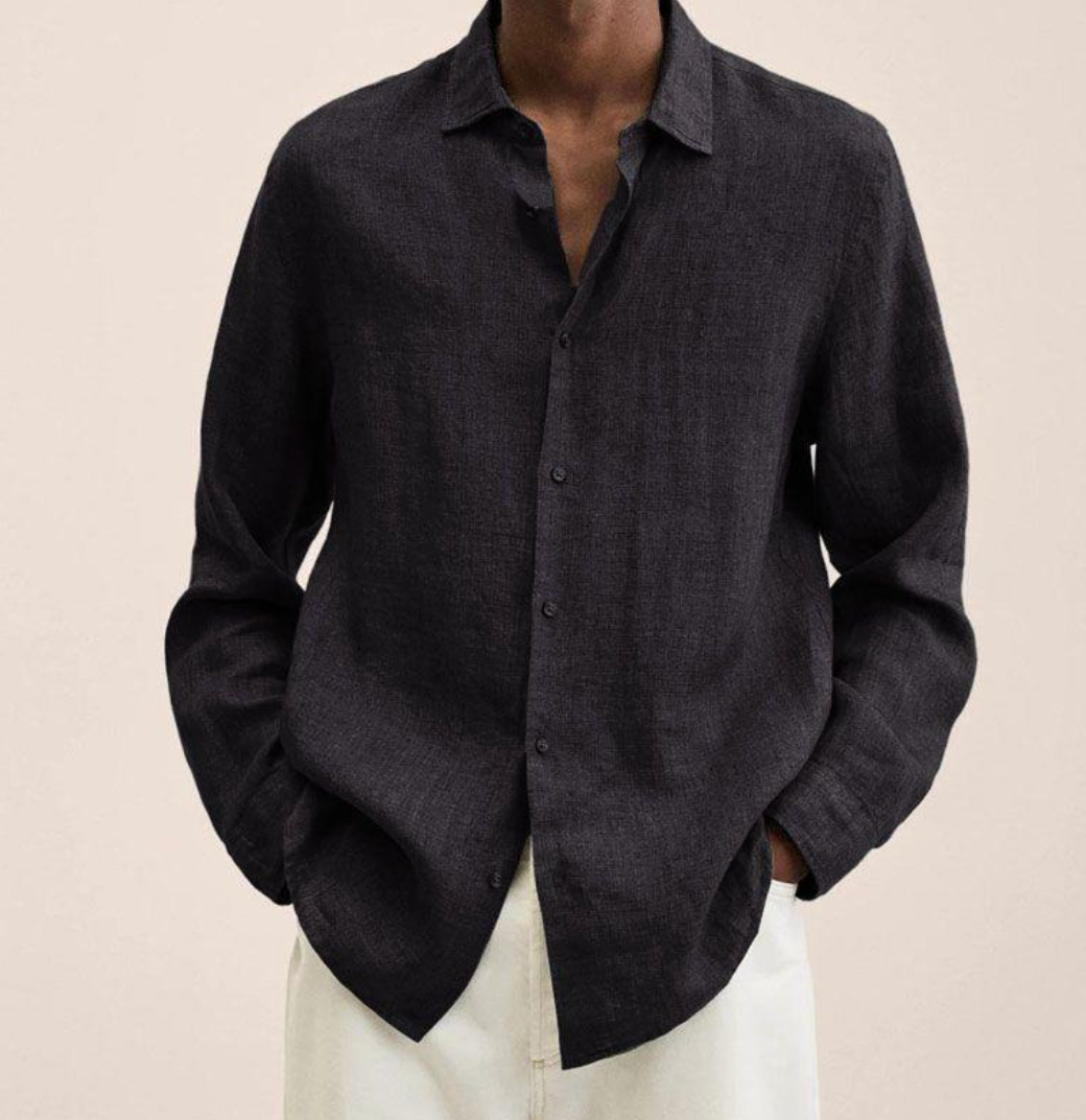 Chemise en lin noir pour homme, manches longues, col ouvert, portée avec un pantalon blanc. Mode masculine élégante et décontractée.