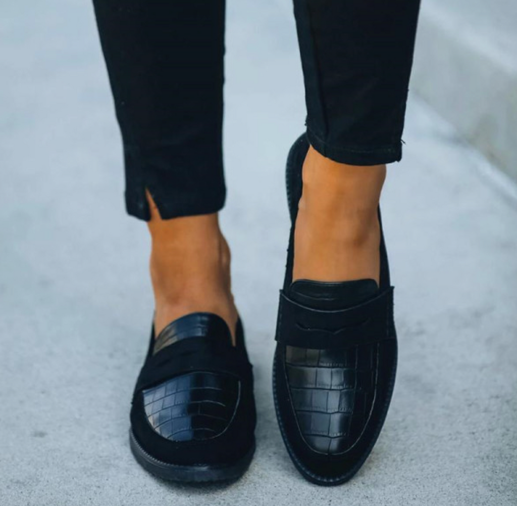 Chaussures mocassins noirs en cuir croco portées avec un pantalon noir. Élégance urbaine, style moderne, mode automne-hiver.