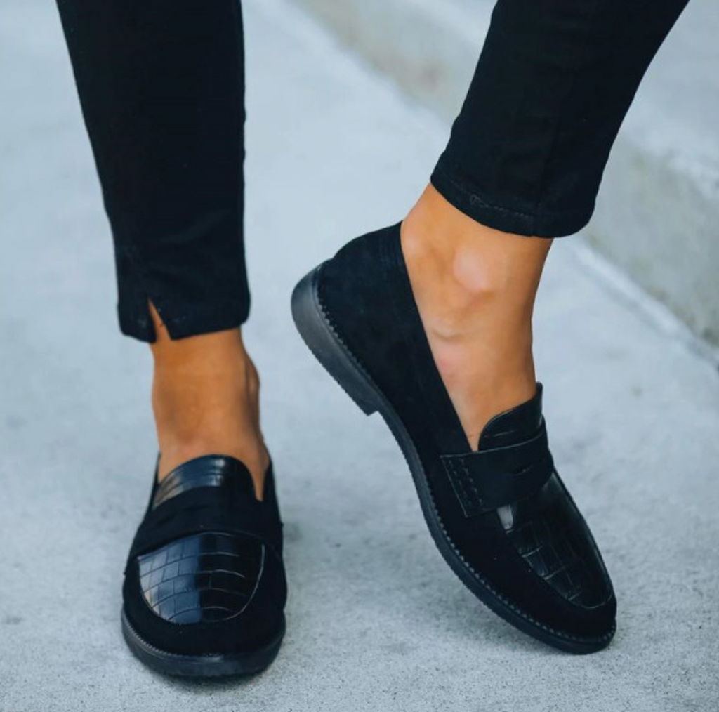 Chaussures mocassins noirs en cuir verni et daim, portées avec un pantalon noir. Style élégant et moderne pour hommes.