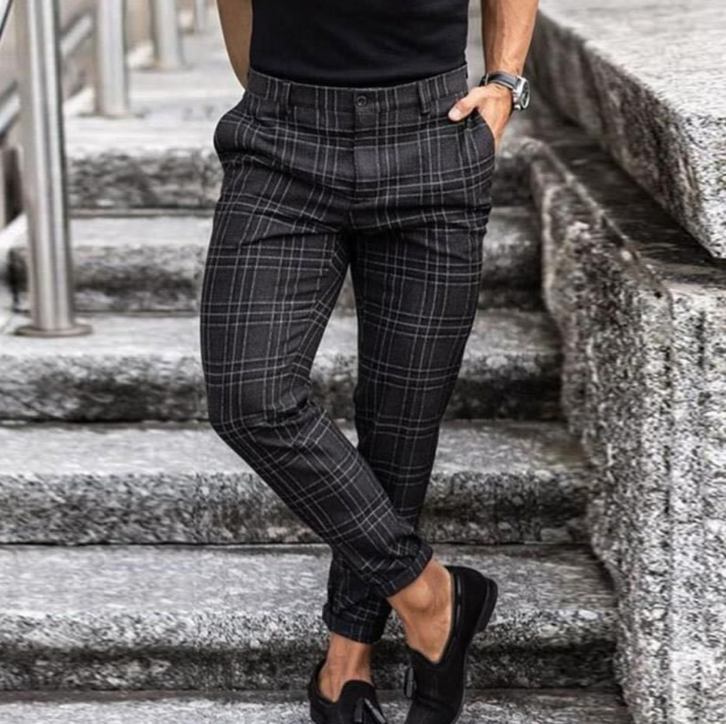 Pantalon à carreaux noir et gris pour homme, style élégant, porté avec des mocassins noirs, mode masculine moderne, escaliers en arrière-plan.