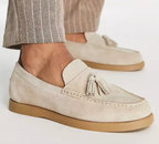 Mocassins en daim beige avec pampilles, semelle en caoutchouc marron, portés avec un pantalon à rayures. Chaussures élégantes pour homme.