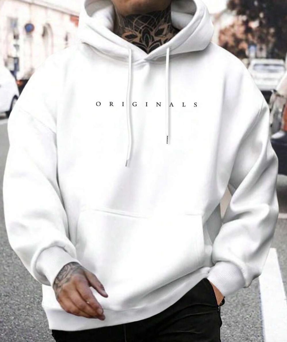 Homme portant un sweat à capuche blanc avec l'inscription "ORIGINALS", tatouages visibles, marchant en ville. Mode urbaine, style décontracté.