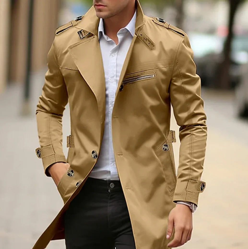 Homme portant un trench-coat beige élégant, chemise blanche et pantalon noir, marchant en ville. Mode masculine, style urbain chic.
