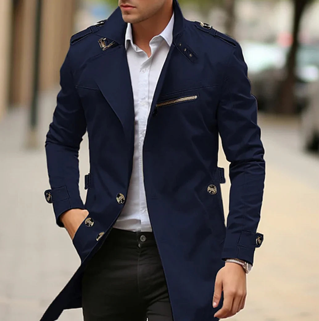 Homme portant un trench-coat bleu marine élégant, chemise blanche et pantalon noir, marchant en ville. Mode masculine, style urbain chic.
