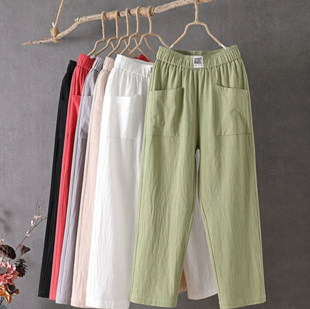 Pantalons en lin suspendus sur cintres, couleurs variées : vert, blanc, rose, gris, rouge, noir. Mode décontractée, vêtements légers pour l'été.