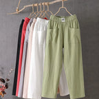 Pantalons en lin suspendus sur cintres, couleurs variées : vert, blanc, rose, gris, rouge, noir. Mode décontractée, vêtements légers pour l'été.