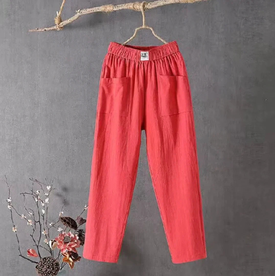 Pantalon rouge en lin suspendu sur une branche, fond gris, style décontracté, poches avant, mode féminine, tendance, confortable, élégant.