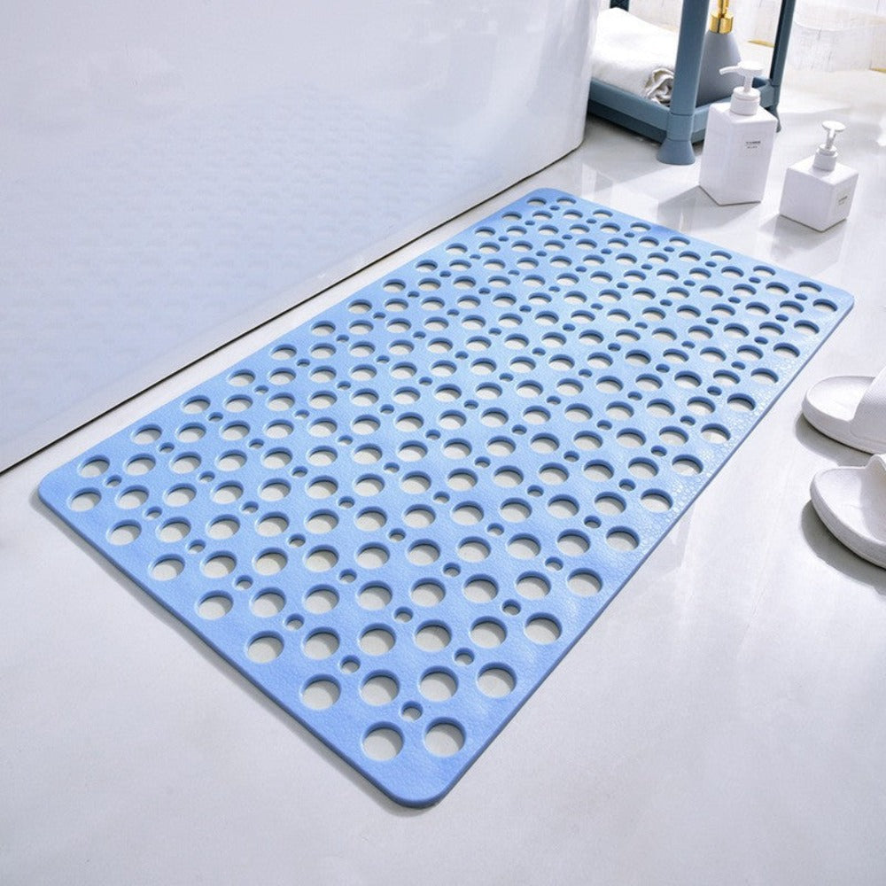 Tapis de bain antidérapant bleu avec trous circulaires, posé sur un sol blanc. Accessoire de salle de bain moderne et sécuritaire.