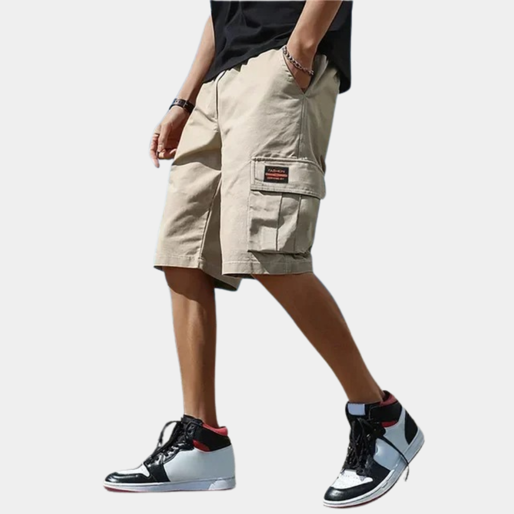Homme portant un short cargo beige avec poches latérales, associé à des baskets montantes noires et blanches. Mode décontractée estivale.