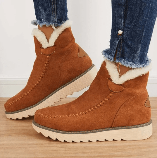 Bottes en daim marron avec doublure en fourrure blanche, semelles crantées, portées avec un jean déchiré. Chaussures d'hiver tendance et confortables.