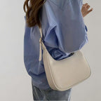 Femme portant une chemise bleue et un sac à main blanc élégant, mode décontractée, style moderne, accessoires tendance, tenue chic.