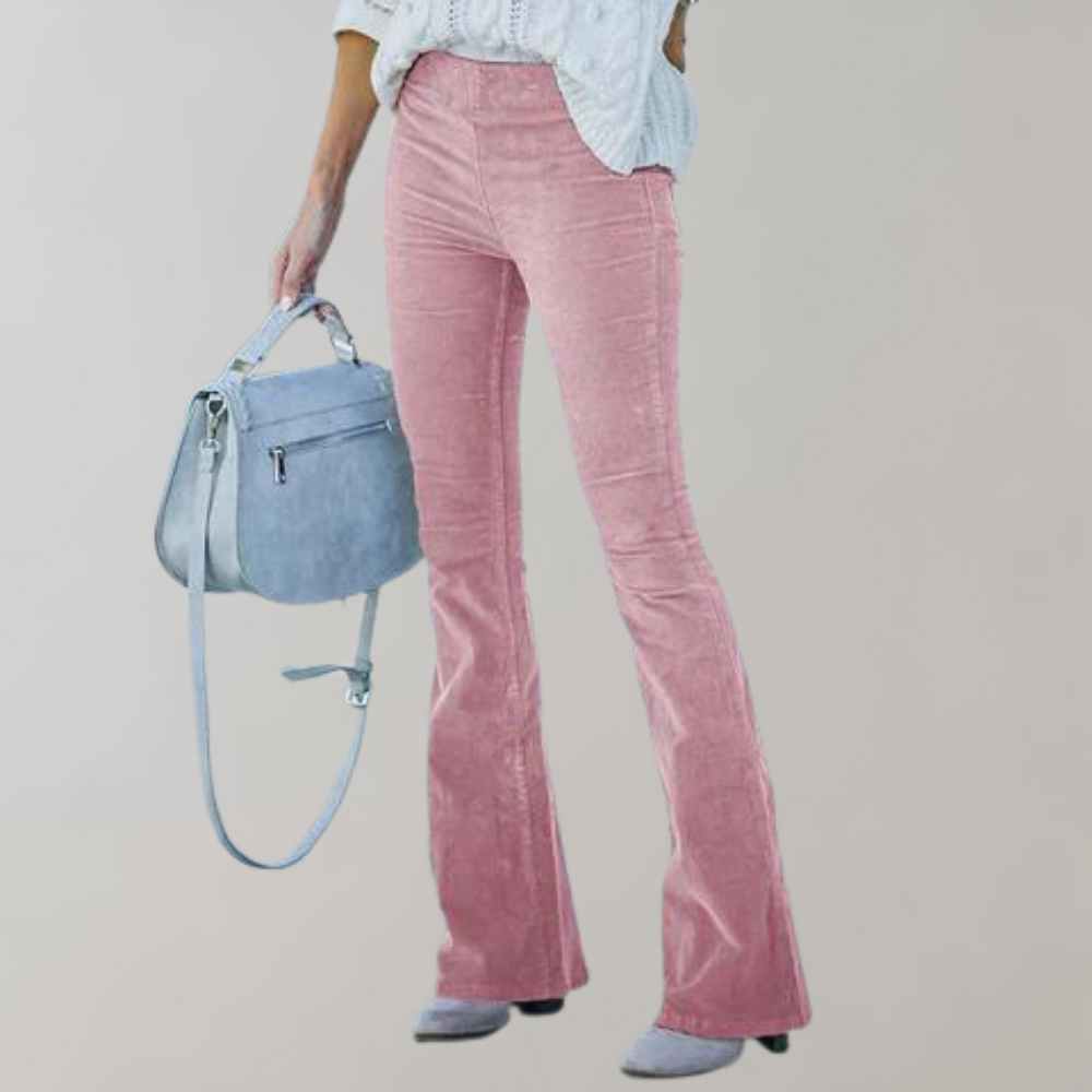 Femme portant un pantalon patte d'éléphant rose en velours côtelé, chemise blanche, et sac à main bleu. Mode féminine élégante et tendance.