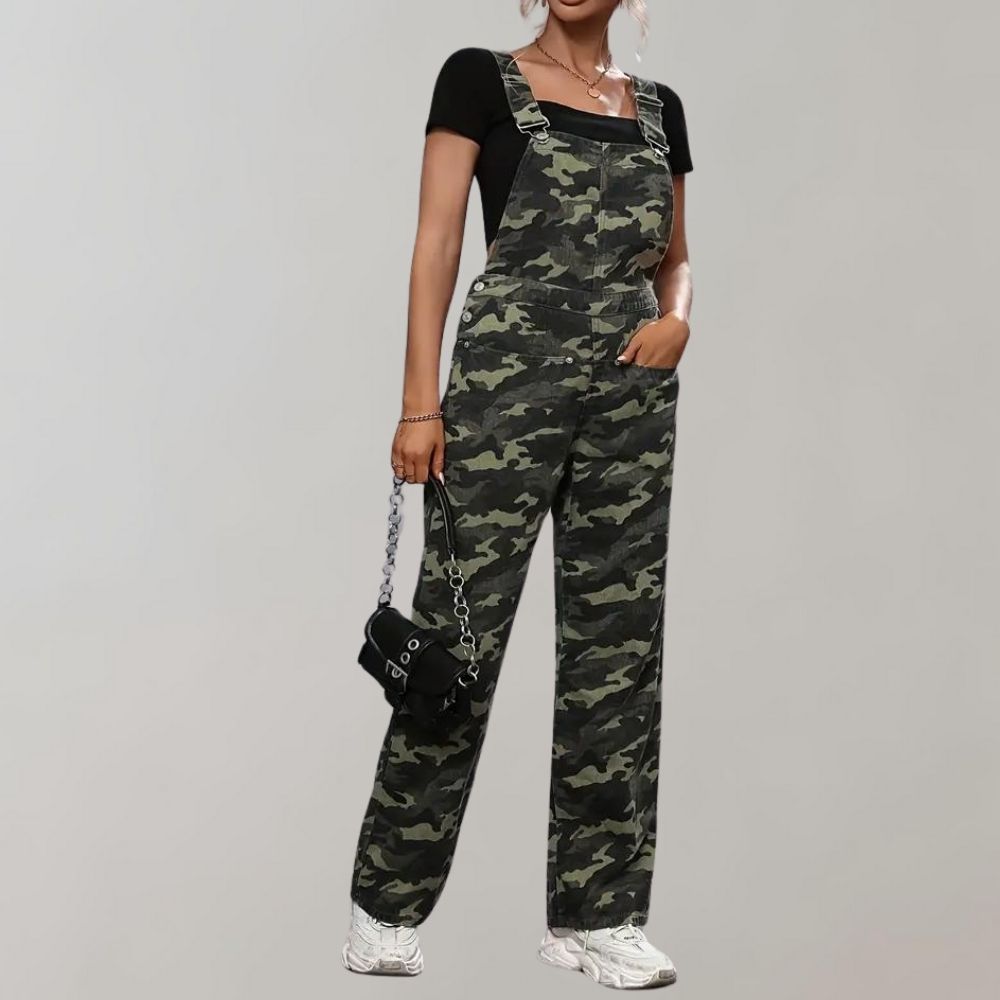 Femme portant une salopette camouflage avec un t-shirt noir, sac à main noir et baskets blanches. Mode urbaine, style décontracté, tendance 2023.