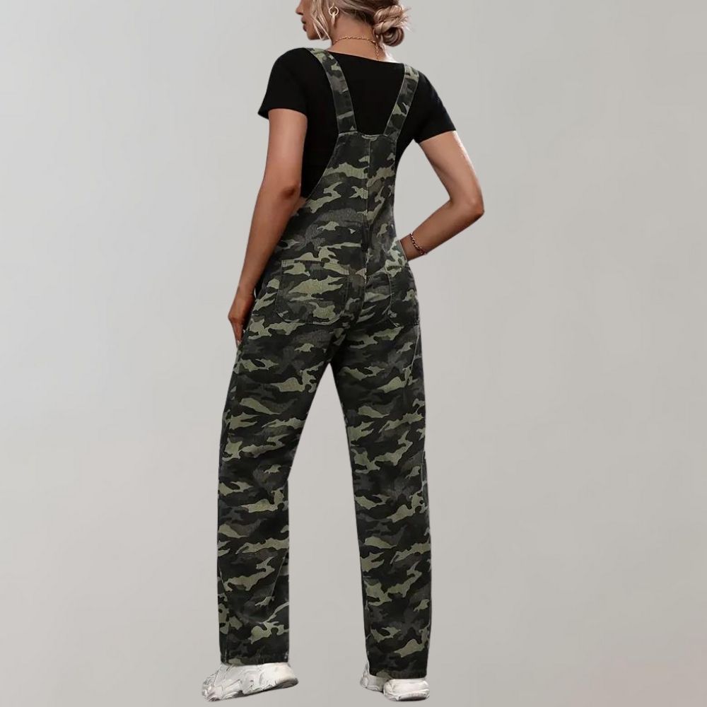 Femme portant une salopette camouflage verte, t-shirt noir et baskets blanches. Mode décontractée, tendance militaire, style urbain.